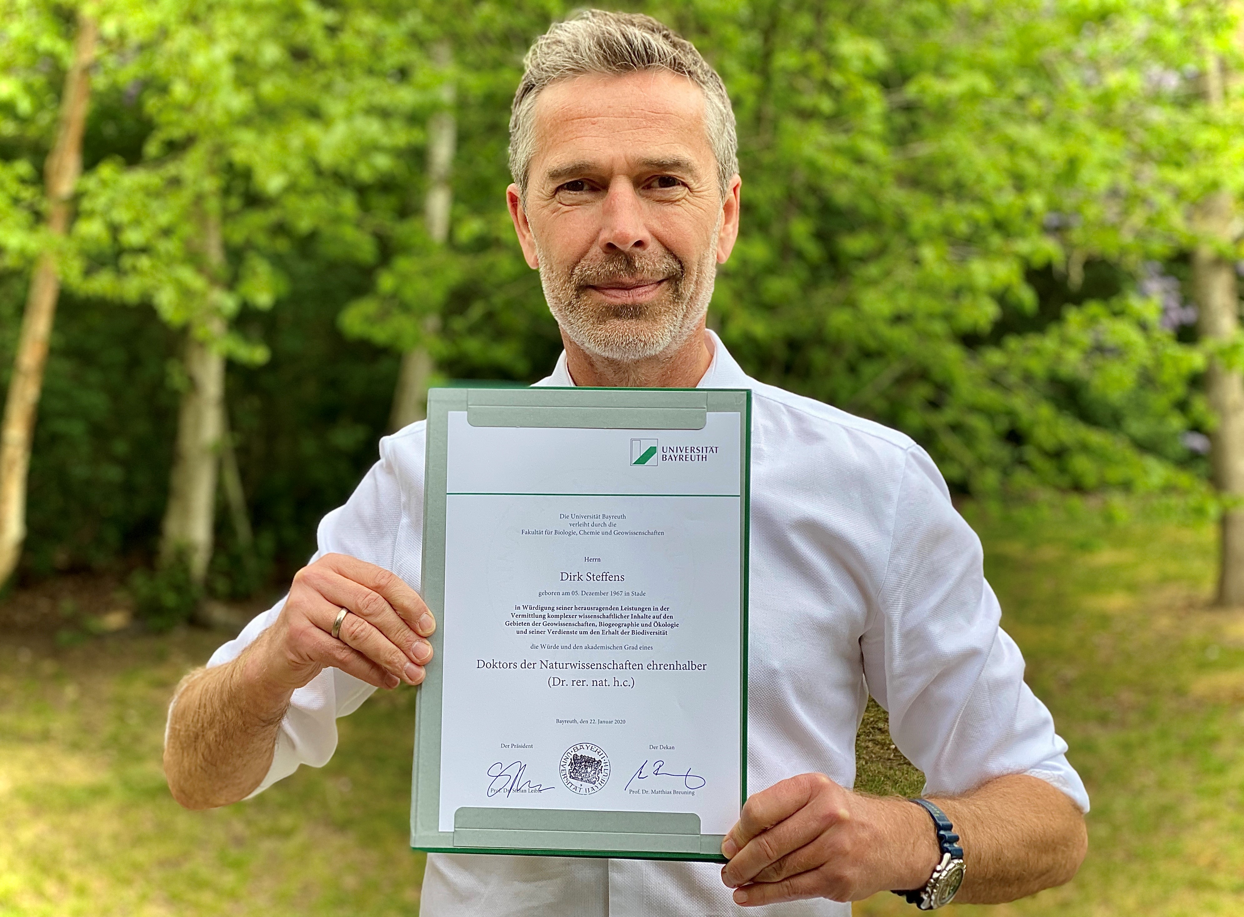 Dirk Steffens präsentiert die Urkunde zur Verleihung der Ehrendoktorwürde der Universität Bayreuth